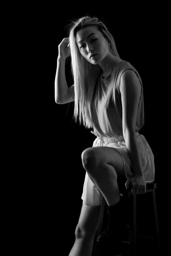 Roland Seichter Fotografie - Fotografie Angebote Shop - Ganzkörperportrait einer jjungen Frau mit langen blonden Haaren auf einem Barhocker lehnend - Schwarz/Weiß