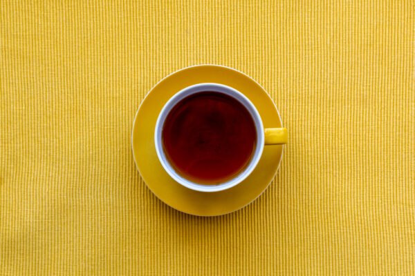 Roland Seichter Fotografie - Einzigartige Wandbilder - Minimalistische Fotografie - Fotografie einer Tasse Tee auf gelbem Setdeckchen von oben