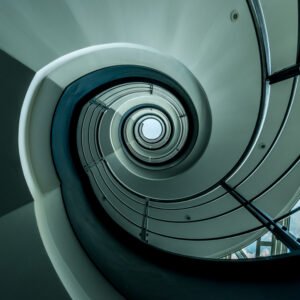 Roland Seichter Fotografie - Einzigartige Wandbilder - Architekturfotografie - Fotografie eines Treppenhauses. Die Geometrie läuft auf einen mittig gelegten Punkt zu.