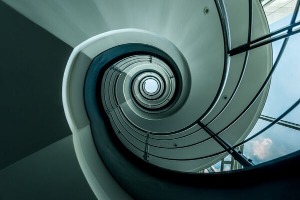 Roland Seichter Fotografie - Einzigartige Wandbilder - Architekturfotografie - Fotografie eines Treppenhauses. Die Geometrie läuft auf einen mittig gelegten Punkt zu.