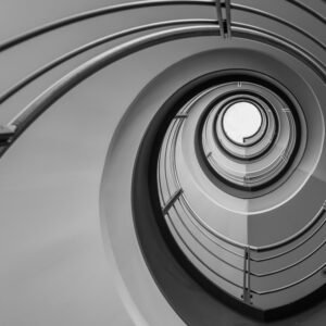 Roland Seichter Fotografie - Einzigartige Wandbilder - Architekturfotografie - Fotografie eines Treppenhauses von unten. Die Geometrie läuft auf einen außermittig gelegten Punkt zu. Schwarz/Weiß