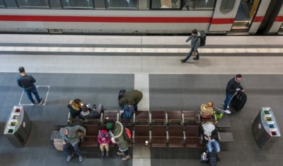 Roland Seichter Fotografie - Städtefotografie - Blick von oben auf einen Bahnsteig im Lehrter Bahnhof Berlin- Menschen sitzen auf einer Bahn, ein ICE-Zug wartet auf dem Gleis