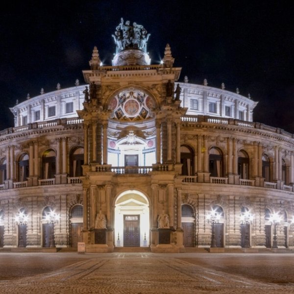 Semperoper Dresden bei Nacht, beleuchtet und mit neoklassischer Architektur.