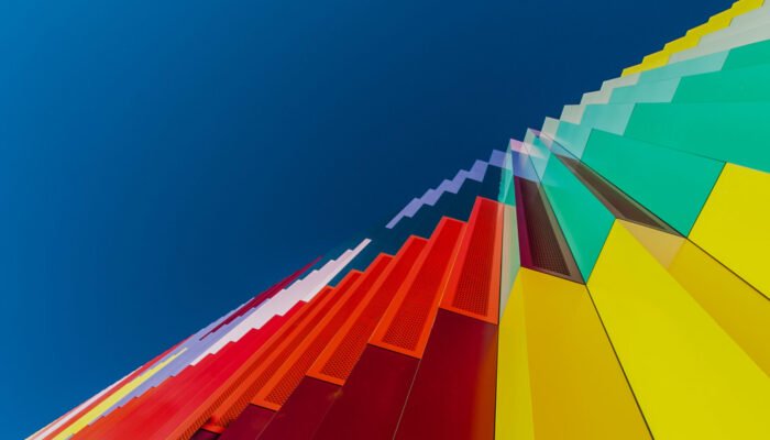 Roland Seichter Fotografie - Fotowettbewerbe - Blick auf eine bunte Fassade von unten. Die Bildkomposition platziert den Rand der Fassade und den blauen Himmel genau in die aufsteigende Diagonale