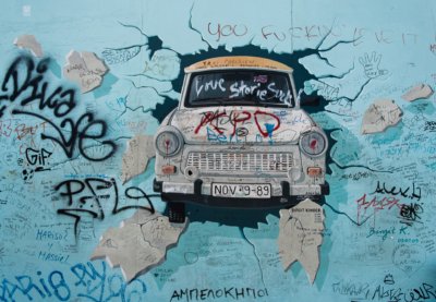 Roland Seichter Fotografie - Städtefotografie - Graffitiy auf einem Berliner-Mauer-Stück. Ein Trabbi bricht durch durch die Mauer.