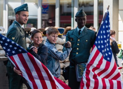 Roland Seichter Fotografie - Städtefotografie - Zwei Jungen posen mit zwei UA-Armeeangehörigen vor amerikanischen Flaggen am Checkpoint Charlie