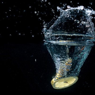 Roland Seichter Fotografie - Experimentelle Fotografie - Gelbe Zitronenscheibe fotografiert eim Eintauchen ins Wasser
