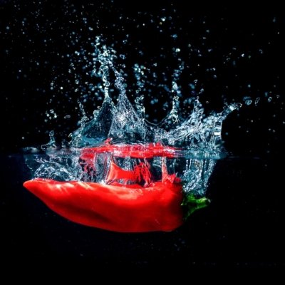 Roland Seichter Fotografie - Experimentelle Fotografie - Rote Spitzpaprika fotografiert eim Eintauchen ins Wasser