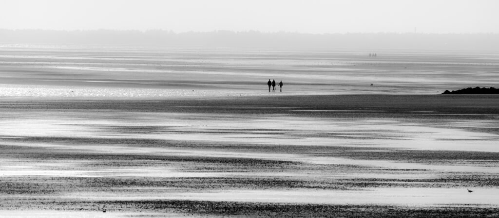 Roland Seichter Fotografie - Minimalistische Fotografie - Im Watt bei Ebbe, 3 Personen weit entfernt - Schwarz/Weiß
