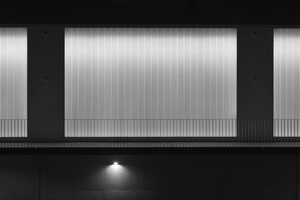 Roland Seichter Fotografie - Minimalistische Fotografie - Eine hinterleuchtete Glasfassade in der Dunkelheit - Schwarz/Weiß