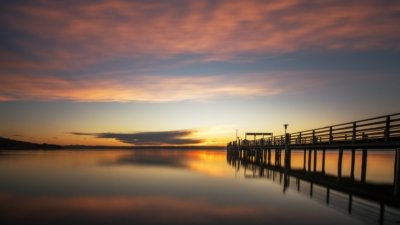 Roland Seichter Fotografie - Landschaftsfotografie - Abends am Ammersee über eine Seebrücke aufs Wasser fotografiert. Die Abendonne erzeugt ein rotes Licht - Variante 2