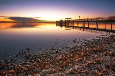 Roland Seichter Fotografie - Landschaftsfotografie - Abends am Ammersee über eine Seebrücke aufs Wasser fotografiert. Die Abendonne erzeugt ein rotes Licht