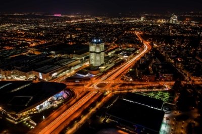 Roland Seichter Fotografie - Städtefotografie - Blick vom Olympiafernsehturm in München auf das BMW Hauptgebäude in der Nacht. Die Langzeitbelichtung zeigt die Fahrzeuge in den Straßen als orange Striche