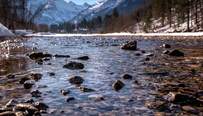 Roland Seichter Fotografie - Einzigartige Wandbilder - Fotografie mit Wasser - Fotografie eines Bergflusses, im Hintergrund eine Bergkette - unscharf