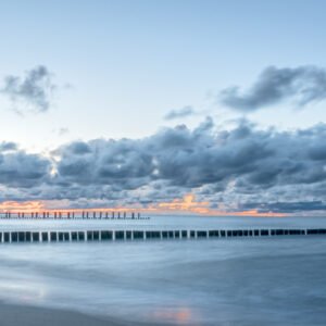 Roland Seichter Fotografie - Einzigartige Wandbilder - Fotografie mit Wasser - Abendstimmung am Meer, Buhnen von links ragen ins Meer. Am Horizont leuchtet noch der Himmel in orange/gelb