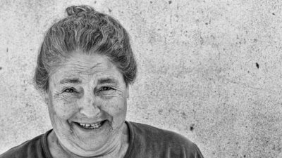 Roland Seichter Fotografie - Streetfotografie - Fotografie einer älteren Frau, die freundlich in die Kamera blickt. Schwarz/Weiß