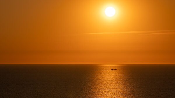 Roland Seichter Fotografie - Einzigartige Wandbilder - Fotografie mit Wasser - Eine Abendstimmung über dem Meer, man sieht die untergehende Sonne, das Bild ist in orange Farben getaucht