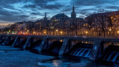 Roland Seichter Fotografie - Fotowettbewerbe - Die Aufnahme eines Wehrs an der Isar in der Abenddämmerung. Die Straße ist schon erluchtet, das Wehr verschwindet im Dunkel