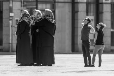 Roland Seichter Fotografie - Streetfotografie - Drei offensichtlich islamistische Damen mit Kopftüchern und zwei jüngere westliche Menschen schaun nach links oben. Man sieht nicht, was da oben ist. Schwarz/Weiß