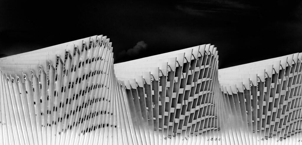 Roland Seichter Fotografie - Architekturfotografie - Die Fassade des Bahnhofes Reggio Emilia mit seinen charakteristischen Wellen. Stark verfremdet, der Himmel ist schwarz. Schwarz/Weiß