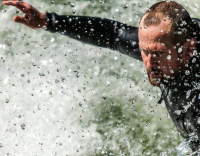 Roland Seichter Fotografie - Sportfotografie - Nahaufnahme eines Surfers mit konzentriertem Blick. Wassertropfen zeigen, dass er bei seinem Sport ist.