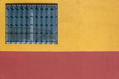 Roland Seichter Fotografie - Minimalistische Fotografie - Ein vergittertes Fenster in einer orange-roten Wand