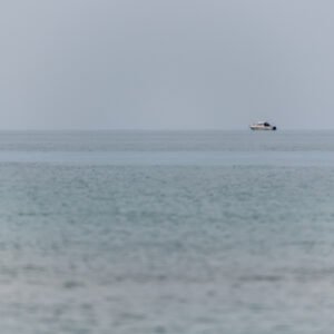 Roland Seichter Fotografie - Einzigartige Wandbilder - Fotografie mit Wasser - Eine minimalistische Fotografie einer Boje und eines kleinen Bootes im Meer