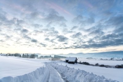 Roland Seichter Fotografie - Landschaftsfotografie - Blick in eine schneebedeckte Straße am Morgen, eine kleine Scheune im Vordergrund, kleine Wolken am Himmel