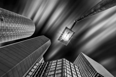 Roland Seichter Fotografie - Städtefotografie - Frankfurt - Blick von unten an Hochhäuser nach oben. Eine Lampe mit einem Lichtstern. Schwarz/Weiß
