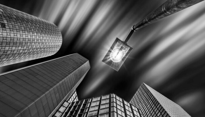 Roland Seichter Fotografie - Städtefotografie - Frankfurt - Blick von unten an Hochhäuser nach oben. Eine Lampe mit einem Lichtstern. Schwarz/Weiß