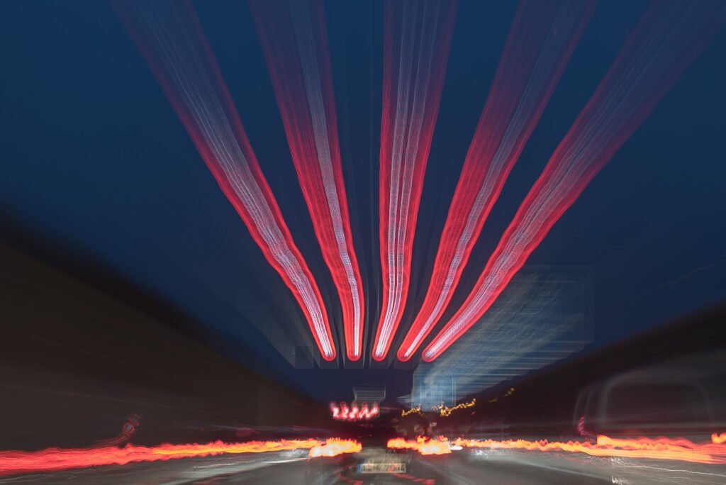 Abstrakte Langzeitbelichtung einer nächtlichen Straße mit dynamischen roten und weißen Lichtspuren von vorbeifahrenden Autos