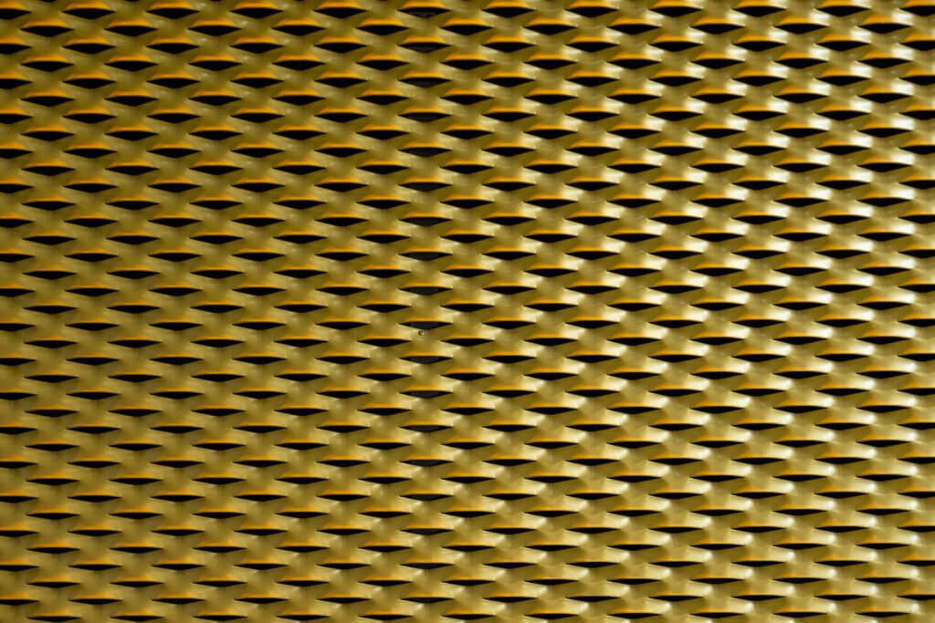 Abstrakte Fotokunst eines goldenen Metallgitters mit rhythmischer Rautenstruktur und Lichtreflexionen