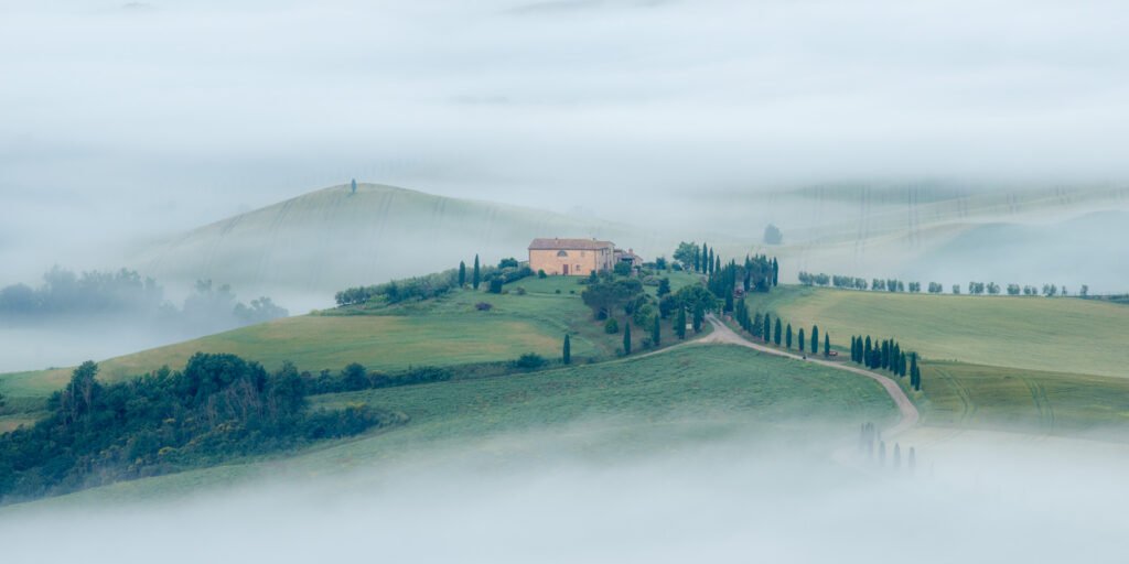 Agriturismo Terrapille in der Toskana, eingebettet in sanfte grüne Hügel und dichten Morgennebel.