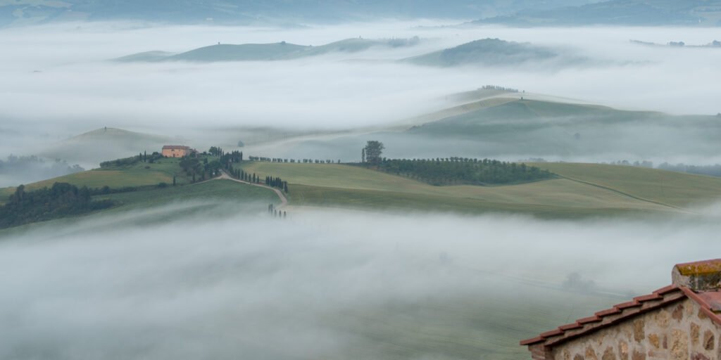 Weite Toskana-Landschaft mit dem Agriturismo Terrapille, das aus einem tief hängenden Nebelmeer hervorragt.