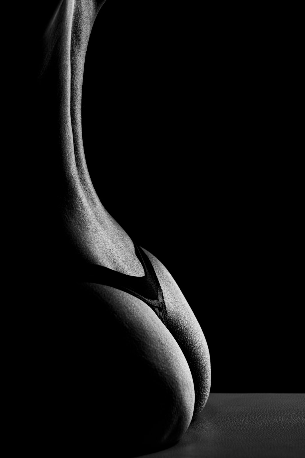 Abstrakte schwarz-weiß Aktfotografie einer weiblichen Rücken-Silhouette mit starken Lichtkontrasten.