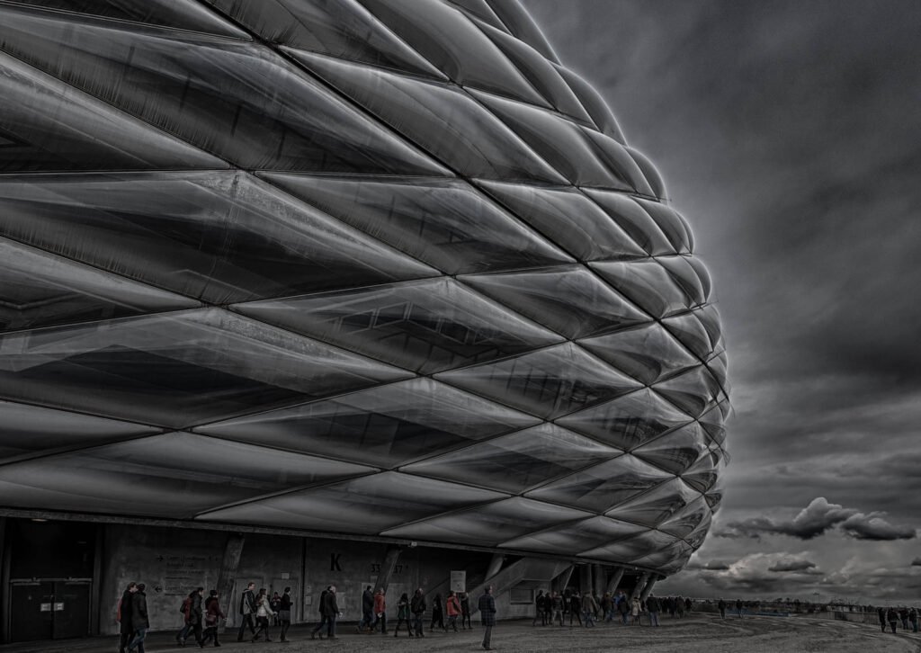 Dramatische Außenansicht der Allianz Arena München bei bewölktem Himmel.