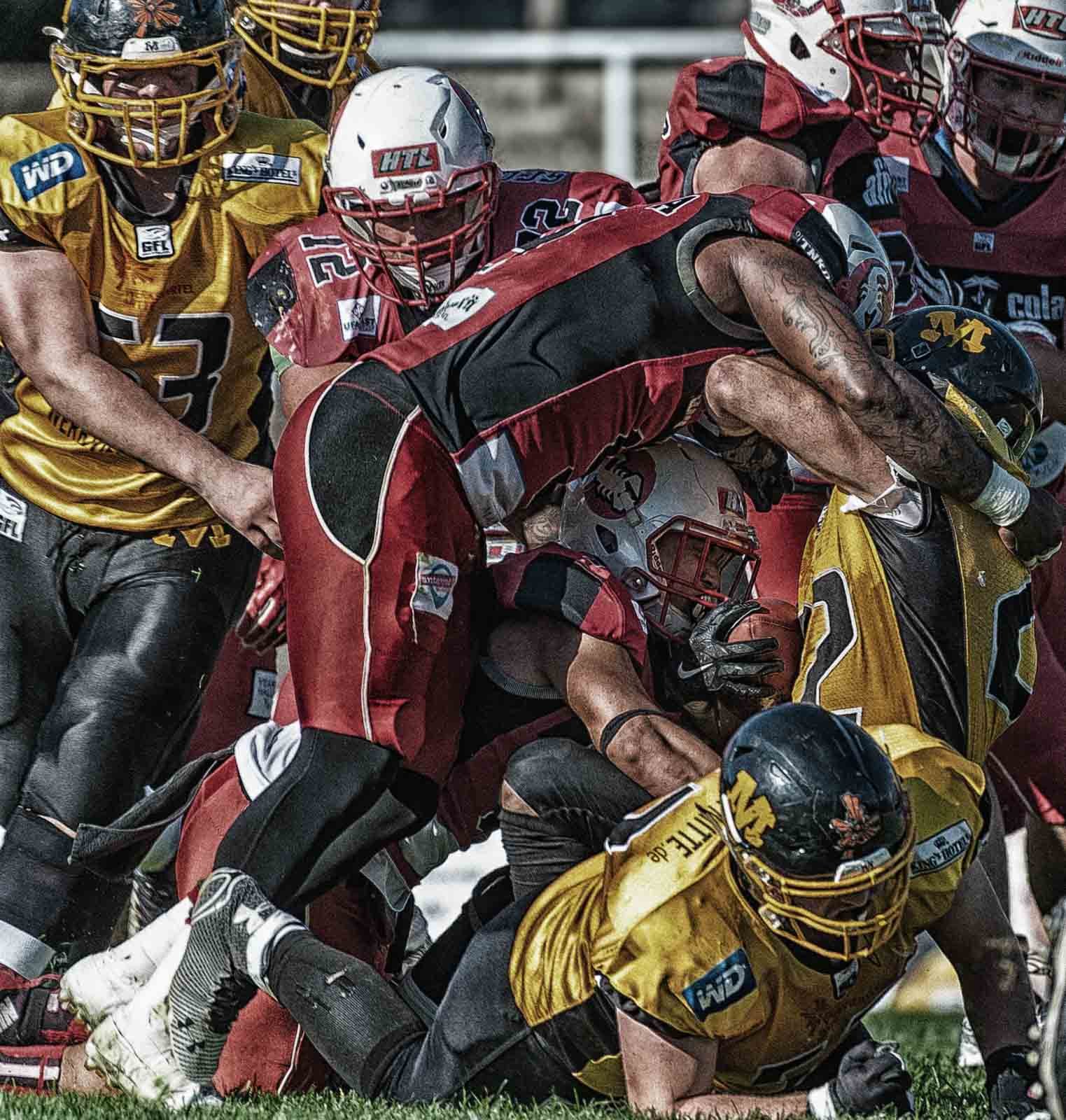 Intensive Spielszene beim American Football: Kampf um den Ballbesitz am Boden.