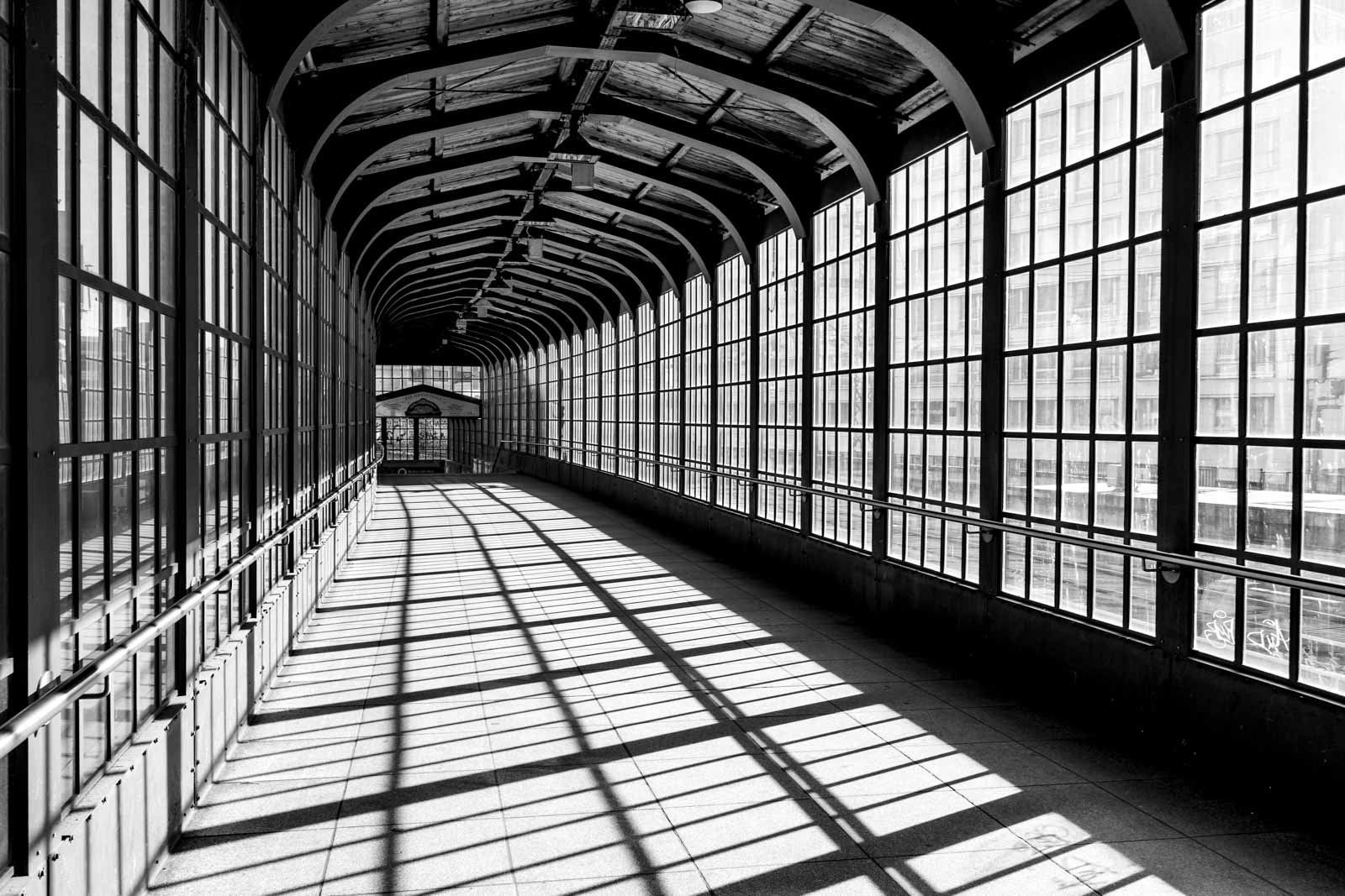 Architekturaufnahme des Bahnhofs Friedrichstraße in Berlin in Schwarz-Weiß mit markantem Licht- und Schattenspiel.