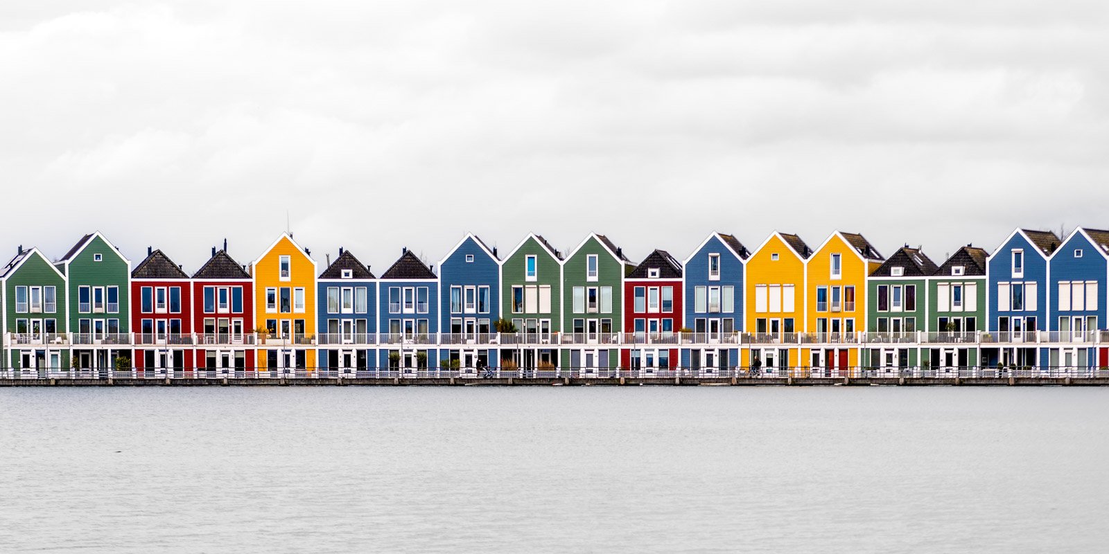 Panoramaaufnahme einer langen Reihe farbenfroher Giebelhäuser direkt an einer Wasserfront.
