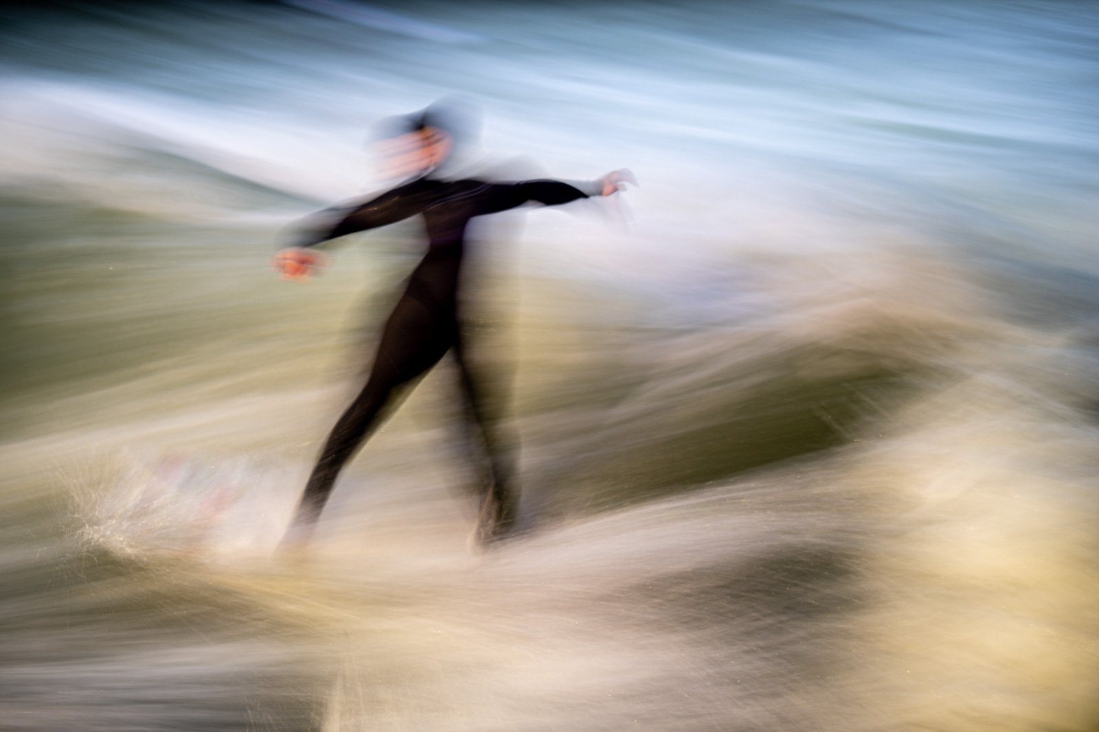 Dynamische Langzeitbelichtung eines Surfers auf der Eisbachwelle in München mit starker Bewegungsunschärfe.