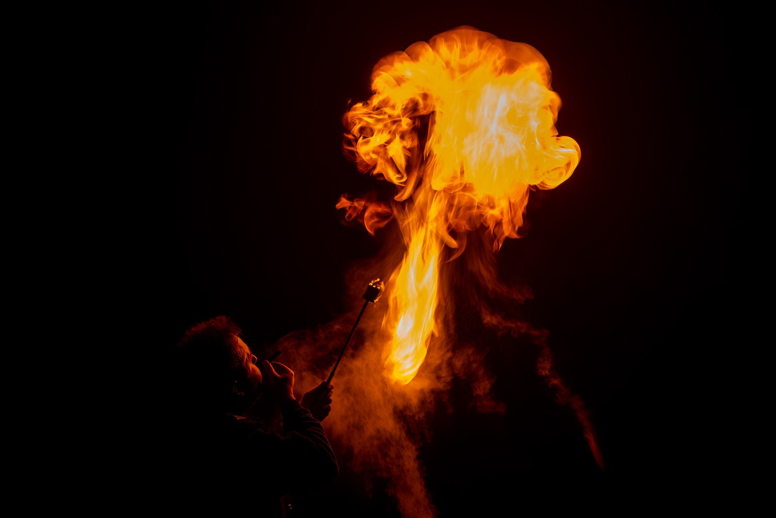 Ein Feuerspucker bei Nacht mit einer großen, detailreichen Feuerwolke.