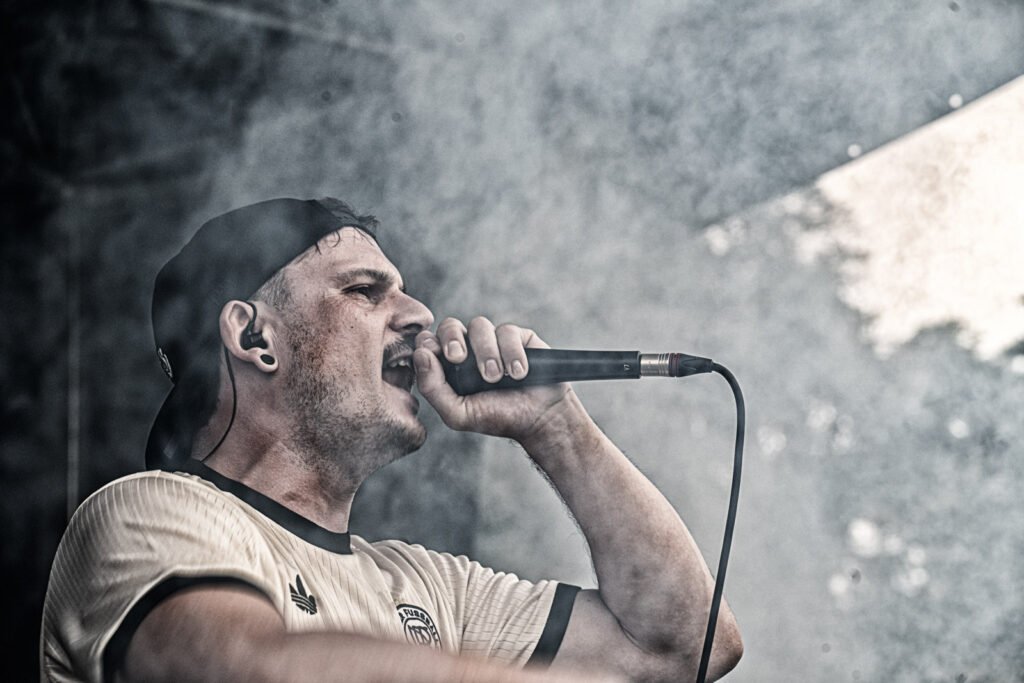 Hautnahe, körnige Live-Fotografie eines schreienden Frontmanns, die rohe Energie des Forest Metal Festivals einfangend. Foto: Roland Seichter