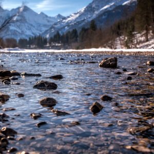 Das Wandbild Bergfluss zeigt klares, glitzerndes Wasser eines Gebirgsbachs im Vordergrund und schneebedeckte Gipfel im Hintergrund