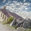 Das Composing Downstairs Underground zeigt einen surrealen U-Bahn-Aufgang, der organisch aus einem Felsen unter einem weiten Wolkenhimmel ragt.