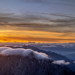 Fotokunst Die Sonne geht auf Zugspitze: Sonnenaufgang mit hellem Schein am linken Bildrand und Reflexionen auf Wolken.