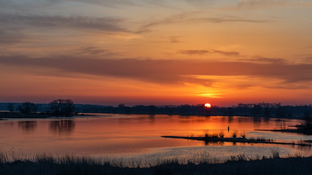 Das Wandbild Elbufer abends zeigt einen stimmungsvollen Sonnenuntergang über der Elbe mit tiefroten Farben und sanften Spiegelungen im Wasser