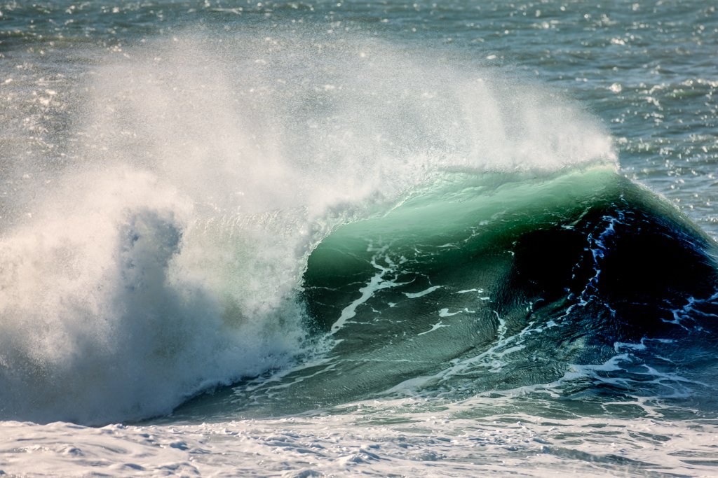 Das Wandbild Grüne Welle zeigt eine brechende, smaragdgrüne Atlantikwelle mit aufstäubender weißer Gischt im Gegenlicht