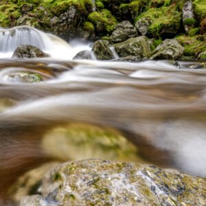 Das Wandbild Riesloch Wasserfall zeigt das dynamisch fließende Wasser in einer weichen Langzeitbelichtung inmitten von moosbedeckten Steinen im Bayerischen Wald