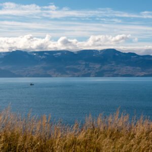 Das Wandbild Ruhige See zeigt einen einsamen Fischkutter auf dem tiefblauen Nordatlantik vor der gewaltigen Kulisse isländischer Berge
