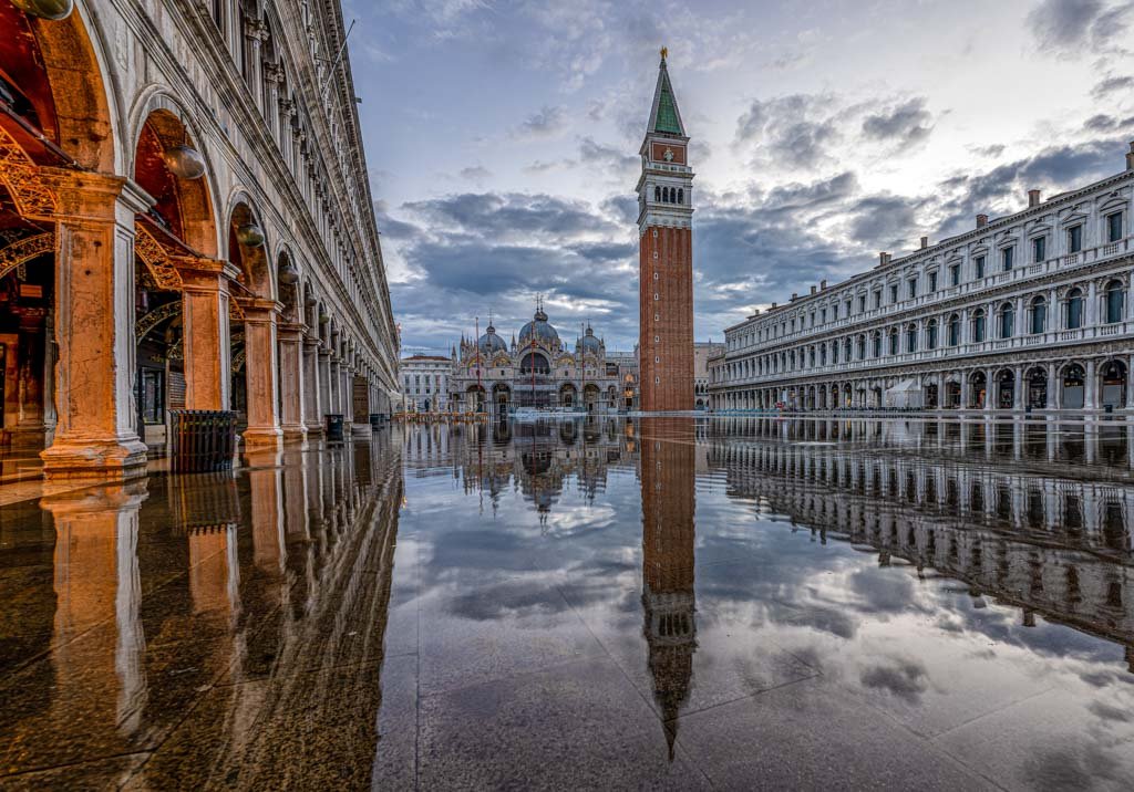 Das Wandbild Acqua Alta zeigt den Markusplatz in Venedig bei Hochwasser mit einer perfekten Spiegelung des Markusturms und der Basilika.